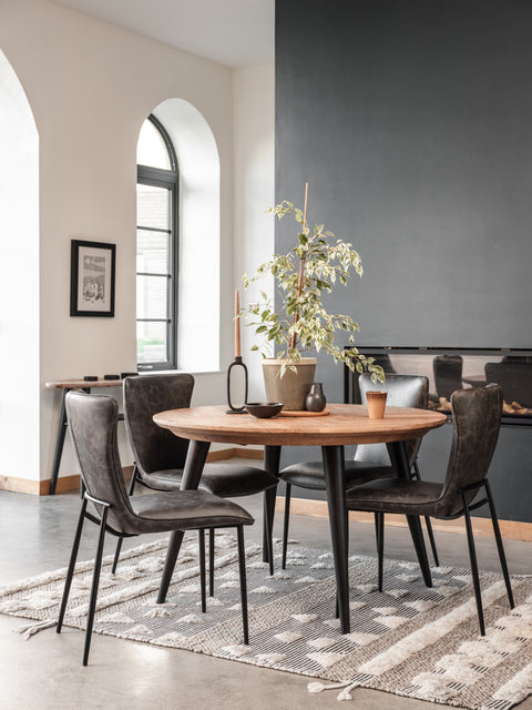 Dining room with a round wooden table and dark chairs on a patterned rug.